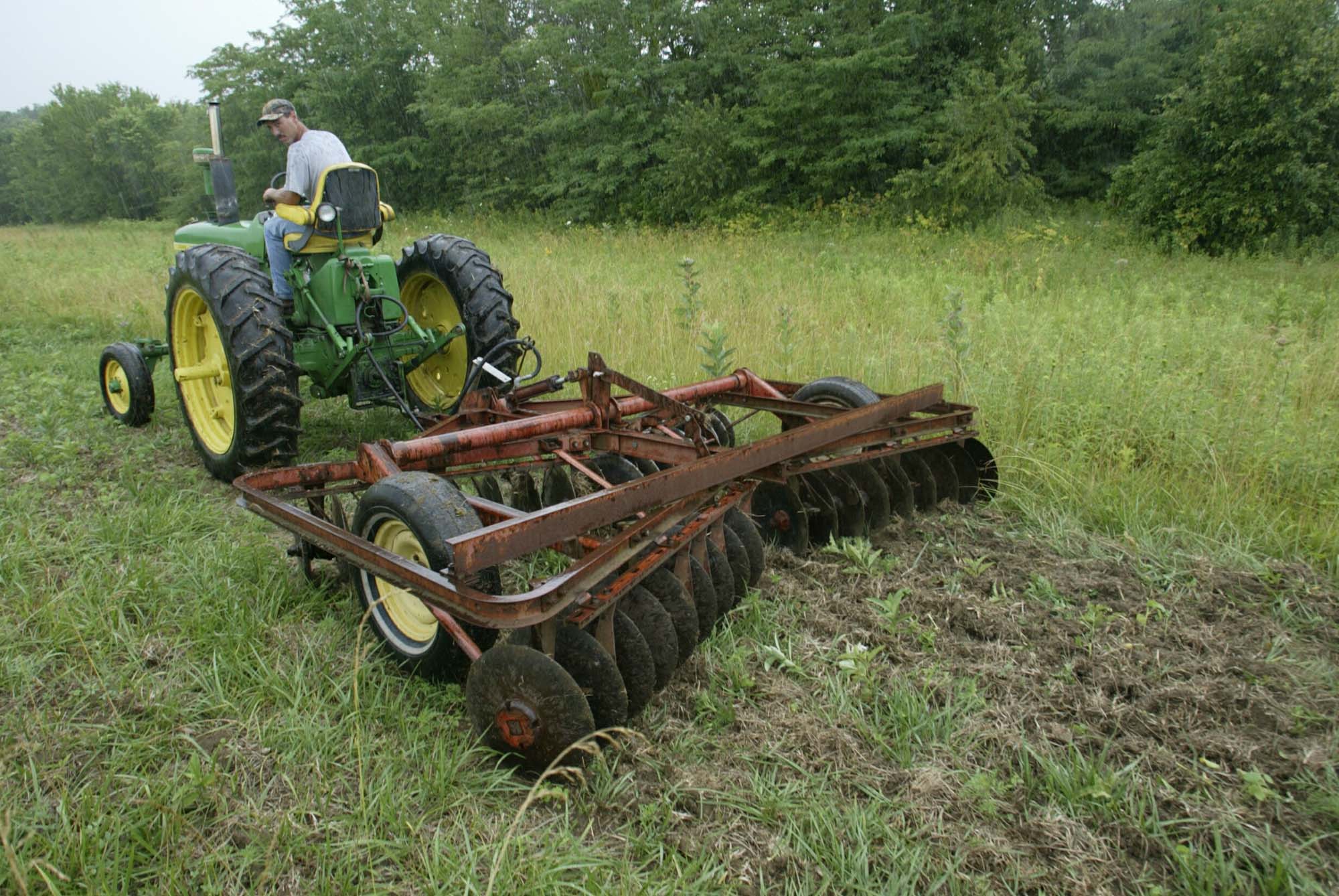 A man on a tractor pulls disk to promote ragweed growth