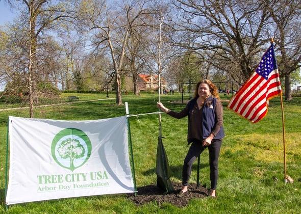 Wendy Sangster stands next to tree planting for Arbor Day award