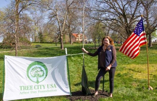 Wendy Sangster stands next to tree planting for Arbor Day award