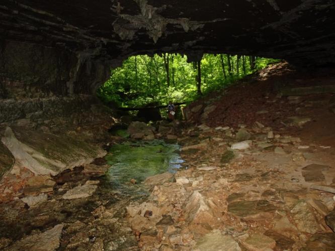 View from within a cave with person standing in front of opening